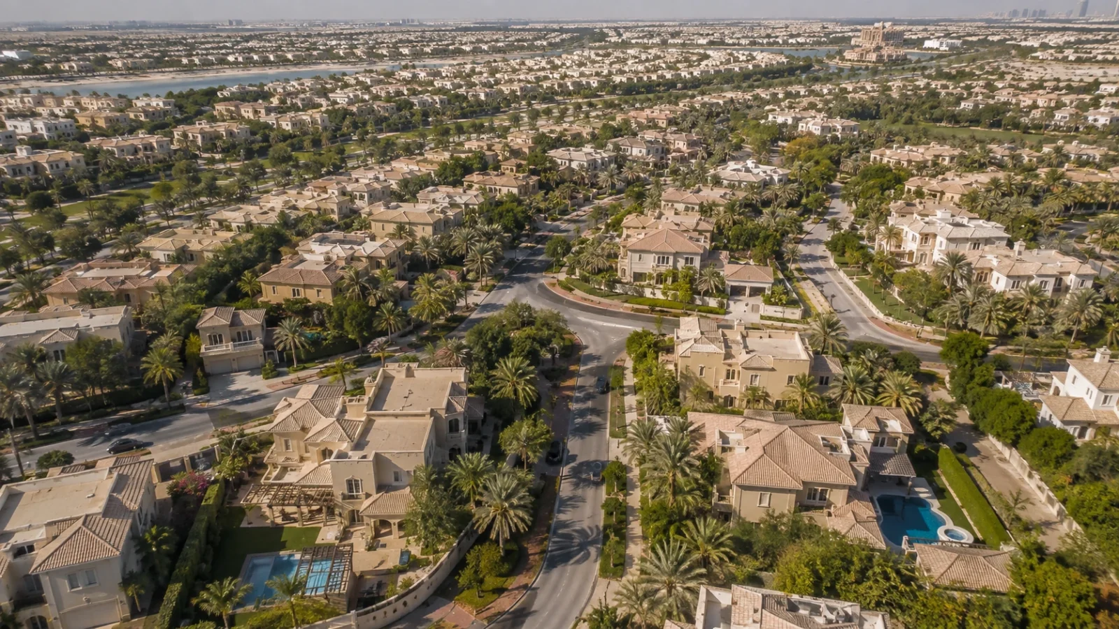 Aerial view of an established Dubai villa community with detached homes, private pools, curving roads and mature landscaping